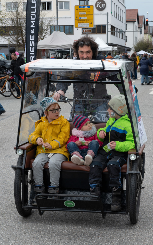 Flo Alt fährt eine Fahrrad-Rikscha. Drei Kinder im Kindergartenalter sind die Passagiere.